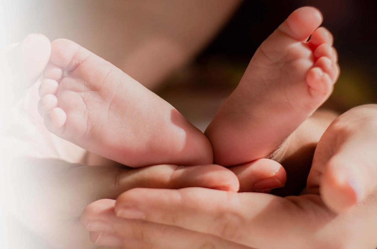 A newborn's feet cupped in a parent's hands