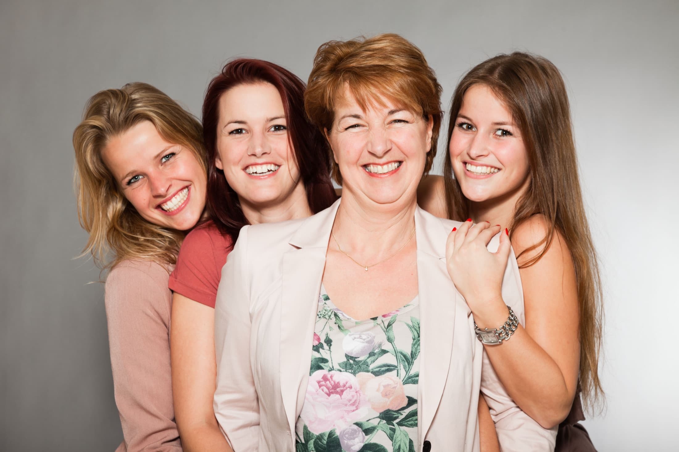 Four women of different ages standing close together and smiling