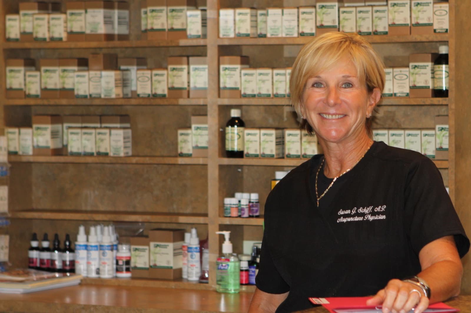 Dr. Susan Schiff smiling behind the front counter, in front of shelves of herbal and nutritional supplements